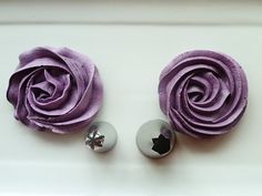 two purple flowers are sitting next to each other on a white surface with silver balls