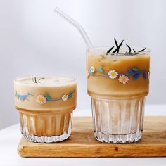 two glasses filled with drinks sitting on top of a wooden tray