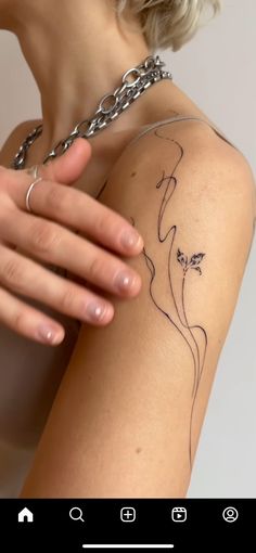 a woman's arm with a tattoo on it and a chain around her neck