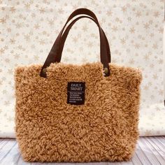 a brown furry handbag sitting on top of a wooden floor next to a wall