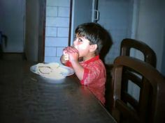 a young boy sitting at a table eating food