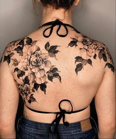 the back of a woman's shoulder with flowers on it and black ribbon around her neck