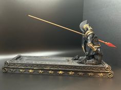 Introducing our striking Gladiator Incense Stick Holder, a fusion of ancient Roman allure and contemporary craftsmanship. Meticulously crafted using advanced 3D printing technology and then lovingly hand-painted, each piece is a testament to precision and artistry. This exceptional creation features a brave Gladiator immortalized, caught in the midst of battle as he meets his destiny with a fatal blow to the back. The carefully designed holder includes a purposeful aperture in the Gladiator's ba Gold And Black Decor, Roman Decor, Fallen Warrior, Unique Bathroom Decor, Warrior Design, Incense Stick Holder, 3d Printing Art, Ancient Technology, Japanese Warrior