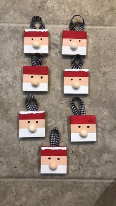 four wooden santa claus ornaments with black and white checkered scarfs on each ornament