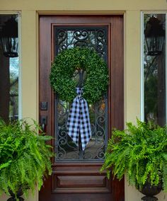 a door with a wreath and two potted plants