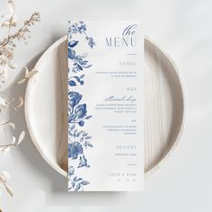 the menu card is sitting on top of a plate next to some flowers and leaves