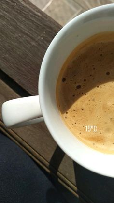 a cup of coffee sitting on top of a wooden table