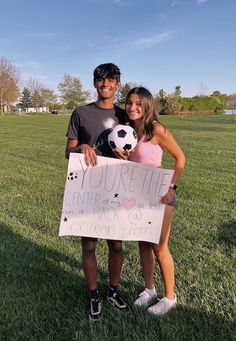 two people standing in the grass holding a sign that says you're the center for soccer