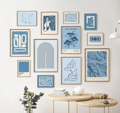 there are many blue and white pictures on the wall above a table with a vase