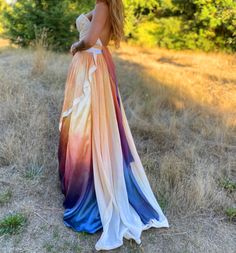 a woman in a long dress is standing in the grass