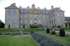 a large building with lots of windows and plants in the front yard, surrounded by lavender bushes