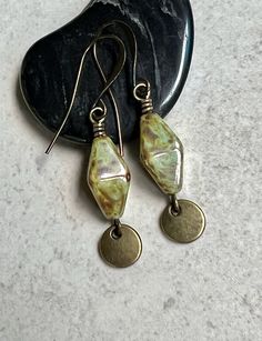 "green boho dangle earrings   green brown czech glass earrings These bi-cone shaped Czech glass beads are light olive green with a brown picasso coating. A small antiqued brass disc dangles below. Hook ear wires are antiqued brass. Length of earrings from top of ear wires is 1 3/4\". Bi-cone beads measure 16mm long. You can enter my shop here: gypsydangles.etsy.com" Earring Inspo, Light Olive Green, Indie Jewelry, Snowflake Earrings, Boho Green, Earrings Green, Exeter, Glass Earrings, Earrings Photo