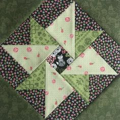 a green and pink patchwork quilt with flowers on the top, along with black and white squares