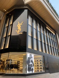 the store front of saint laurent is lit up with gold letters and an image of a man