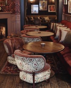 a restaurant with tables, chairs and couches in front of a fire place on the wall