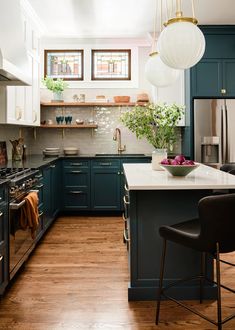 a kitchen with blue cabinets and white counter tops, two hanging lights above the island