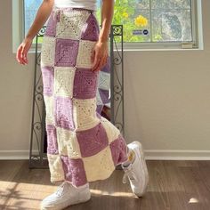 a woman standing in front of a window wearing a purple and white crocheted skirt