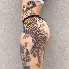 a woman's leg with tattoos on it and a tiger tattoo on the side