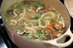 a pot filled with noodles and vegetables on top of a stove