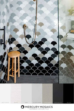 a bathroom with black and white tiles on the shower wall, wooden stool next to it