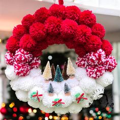 a christmas wreath hanging from the ceiling with pom - poms on it's sides