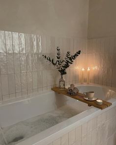 a bathtub with candles and flowers in the corner, next to a candle holder