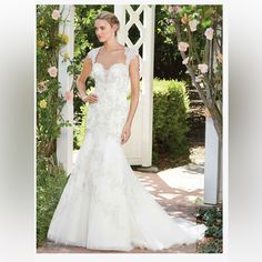 a woman in a wedding dress standing under an arbor