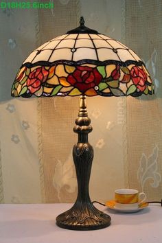 a table lamp sitting on top of a table next to a cup and saucer