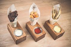 three small wooden trays with different types of food on them