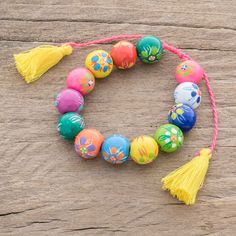 a bracelet with colorful beads and tassels on a wooden surface