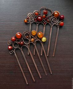 six metal hair pins sitting on top of a wooden table next to oranges and yellows