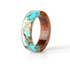 a wooden ring with turquoise and brown flowers inlayed to the inside, on a white background