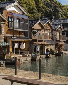 several houses on stilts next to the water with clothes hanging from their balconies