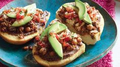 three pieces of bread with meat and avocado on top sitting on a blue plate