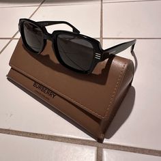 Brand New Burberry “Eldon” Be4349 Comes With Sunglass A Light Brown Case, Still Wrapped Lens Cloth And Matching Brown Color Soft Dust Bag. Brand New Never Worn Discover Burberry Eldon, A Sophisticated Embodiment Of The Iconic British Label's Timeless Elegance. The Solid Dark Grey Lenses And Black Frame Exude Sophistication, While The Key Bridge Adds A Touch Of Modernity To This Rectangle Shape Model Crafted In High-Quality Acetate. Elevated By Its Unique Details Such As The Distinctive Burberry Designer Sunglasses With Tinted Lenses For Everyday, Luxury Brown Shield Sunglasses With Square Frame, Luxury Brown Rectangular Shield Sunglasses, Burberry Astley Sunglasses, Affordable Brown Anti-reflective Shield Sunglasses, Burberry Accessories, Burberry Sunglasses, Bag Brand, Black Sunglasses