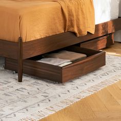 a bed with an open drawer underneath it on top of a carpeted floor in a bedroom