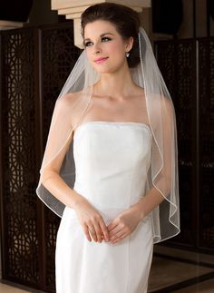 a woman in a white wedding dress with a veil on her head, posing for the camera