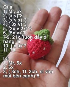 a small crocheted strawberry sitting on top of someone's hand in front of a calendar