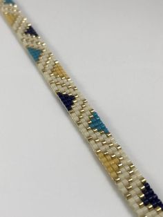 a close up of a bracelet on a white surface with blue and yellow beads in the middle