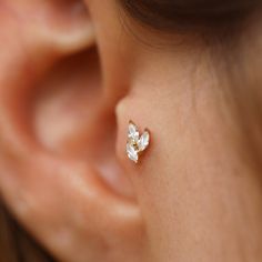 a woman's ear is adorned with two small white flower studs, both in gold and silver