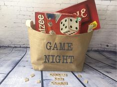 a bag filled with game night items on top of a wooden table next to letters and dice