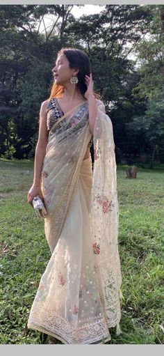 a woman in a sari walking through the grass with her hand on her hip