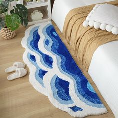 a blue and white rug sitting on top of a wooden floor next to a bed