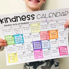 a young boy holding up a calendar for kindness