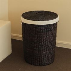 a black wicker basket sitting on the floor next to a white box with a lid