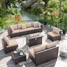 an outdoor furniture set on a deck with flowers and trees in the background, including couches and tables