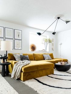 a living room with yellow couches and pictures on the wall above it, along with rugs