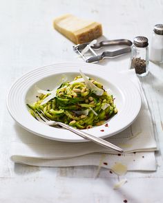 a white bowl filled with food on top of a table next to utensils