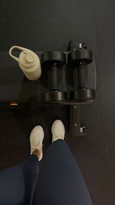 a person standing on a shelf with their feet propped up next to some cups and an object