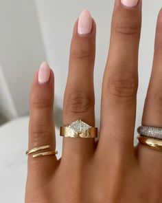 three different types of rings on someone's hand, one with a diamond in the middle